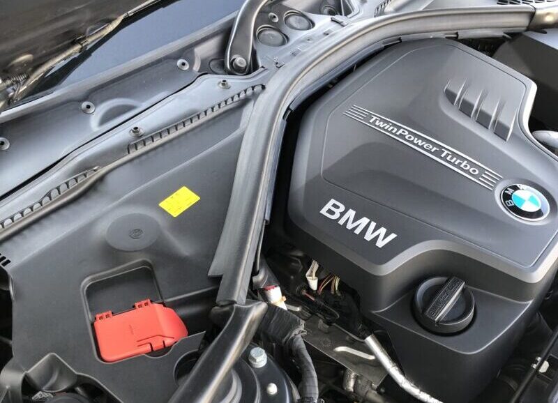 ボンネットを開けたBMW F30 320i Mスポーツのエンジンルーム。BMWロゴと「TwinPower Turbo」のエンジンカバーが大きく写っている